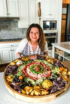 a woman standing in front of a large platter of food