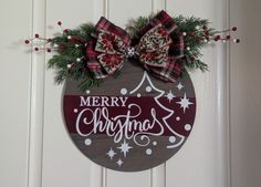 a merry christmas ornament hanging on a door with red and white bowknots