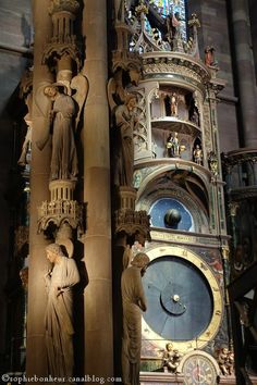 an ornate clock in the middle of a building with statues on it's sides