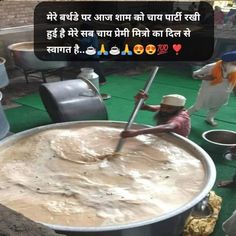 a man is stirring something in a large pot on the ground with other people around him