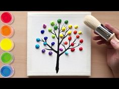 someone is painting a colorful tree on a canvas with acrylic paint and a brush