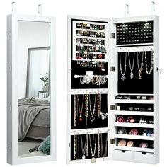 an open white cabinet with jewelry hanging from it's sides and a mirror behind it