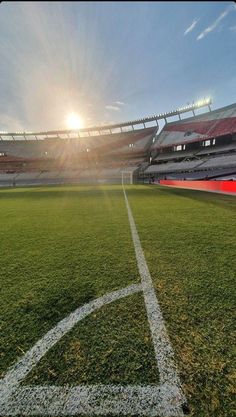 an empty soccer field with the sun in the background