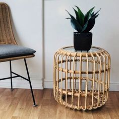 a wicker table with a potted plant on top and a chair next to it