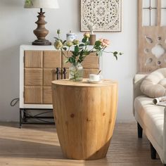 a vase with flowers sitting on top of a wooden table next to a white couch