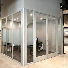 an office with glass walls and desks in the center, surrounded by other cubicles