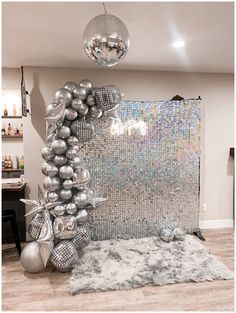 a room decorated with silver balloons and disco ball decorations on the wall, along with a white shaggy rug