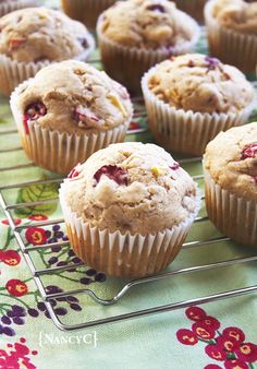 several muffins sitting on a cooling rack next to each other with cranberries in them