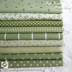 a stack of green and white fabric on top of a table cloth, with the words happy