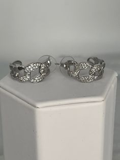 The Silver CZ Chain Huggie Earrings present a modern twist on classic elegance, featuring small, huggie-style hoops in polished silver, from which dangle delicate chains adorned with cubic zirconia stones that shimmer with every turn. These earrings offer a subtle yet striking sparkle, perfect for adding a touch of glamour to everyday outfits or elevating evening wear with their unique, eye-catching design. Length: 22.7 mm Width: 21.3 mm Closure: Bullet with Disc Backs Material: Brass with Silve Elegant Silver Huggie Earrings For Party, Trendy Silver Cubic Zirconia Earrings, Chic Silver Diamond Earrings, Silver Chain Hoop Earrings As Gift, Trendy Silver Hoop Earrings With Chain, Elegant Silver Sparkling Huggie Earrings, Silver Diamond Huggie Earrings Tarnish Resistant, Trendy Silver Hoop Earrings With Adjustable Chain, Elegant Silver Cubic Zirconia Huggie Earrings