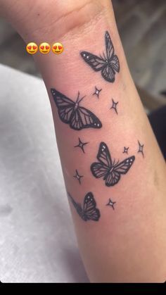 a woman's arm with three butterflies on it and four stars around the wrist