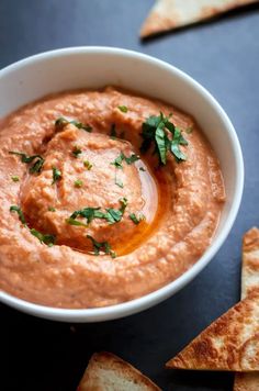 a white bowl filled with hummus and pita chips on top of a table