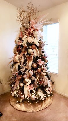 a decorated christmas tree in the corner of a living room with pink and white decorations