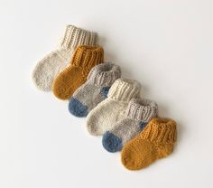 five pairs of baby socks are shown on a white surface, one is yellow and the other is blue