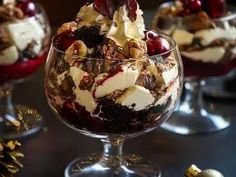 three desserts in glass bowls with fruit and nuts on the top, sitting on a table