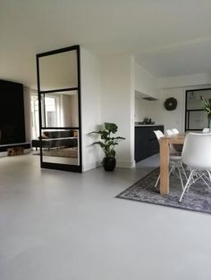 a dining room table with white chairs and a large mirror