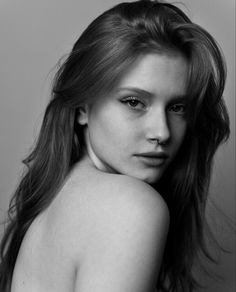 a black and white photo of a woman with long hair wearing a halter top