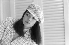 black and white photograph of a woman wearing a plaid shirt with a hat on her head