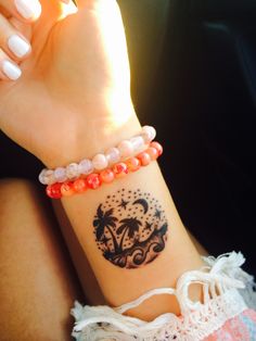 a woman's wrist with a tattoo on it and an orange beaded bracelet