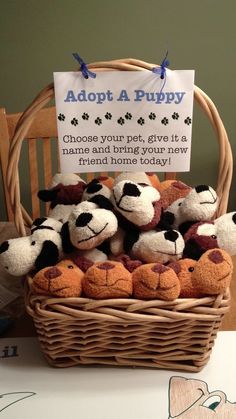 a basket filled with stuffed animals sitting on top of a table next to a sign that says adopt a puppy