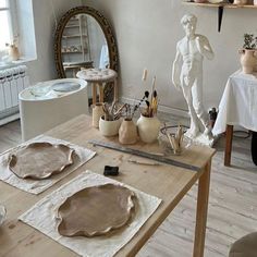 the table is set up with pottery and other things to make it look like an artist's studio