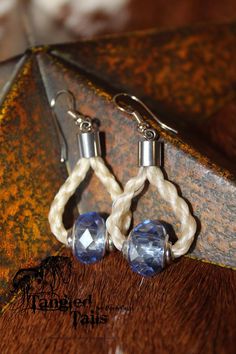 two pairs of earrings with white and blue beads on top of a brown cowhide