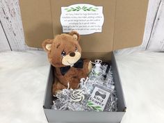 a brown teddy bear sitting inside of a box filled with silver tinsel and bottles