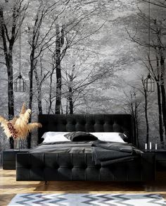 a black and white bedroom with trees on the wall, bed in front of it