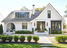 a white house with lots of windows and plants in front of the entrance to it