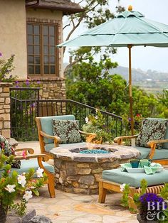 an outdoor patio with chairs, table and umbrella over the fire pit in front of it