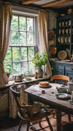 an old fashioned kitchen table and chairs in front of a large window with potted plants on it