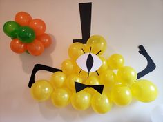 balloons are arranged in the shape of a face and nose on a white wall next to an orange balloon