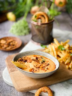 there is a bowl of soup and some fries on the table