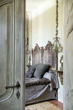 a bed sitting inside of a bedroom next to an open door with ornate carvings on it