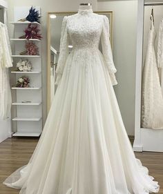 a wedding dress is displayed in front of a mirror with other dresses on display behind it