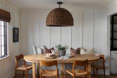 a dining room table with chairs and a basket hanging from the ceiling