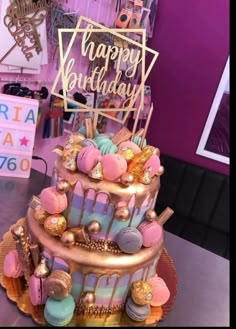 a three tiered birthday cake with lots of decorations on it's side and a happy birthday sign above the top