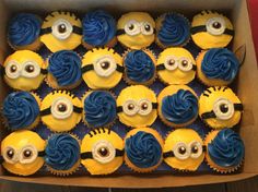 a box filled with yellow cupcakes covered in blue frosting and minion eyes