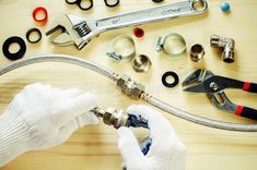 plumbing tools are laid out on a table with gloves, wrenches and hoses