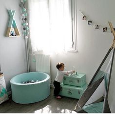 a young child playing in a play room with furniture and decor on the walls, including a teepee tent