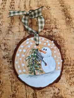 a wooden ornament with a snowman holding a pine tree on it's side