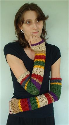 a woman is posing with her hand on her face and wearing colorful knitted arm warmers