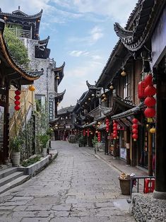 an empty street lined with tall buildings and red lanterns hanging from the side of it