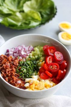 a white bowl filled with different types of food next to lettuce and eggs