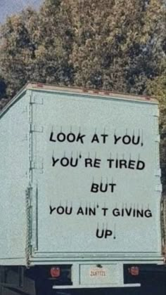 a truck with a sign on the back saying, look at you, you're tired but you ain't giving up