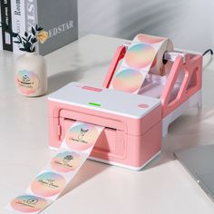 a pink and white machine sitting on top of a table next to a laptop computer