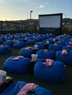 blue bean bag chairs sitting on top of a grass covered field next to a movie screen