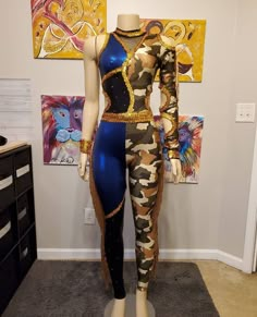 a mannequin wearing a blue and gold bodysuit in front of some paintings