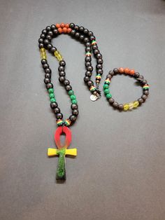 "The \"Rasta Harmony\" Mala Necklace and Bracelet Set is a vibrant and captivating ensemble that combines the essence of Rastafarian culture with the harmonizing energies of Black Wood, Citrine, Red Agate, Malachite, Rasta Beads, and an Ankh pendant. The necklace features round beads made from Black Wood, known for its grounding and protective qualities. The deep black color of the wood creates a strong contrast against the vibrant Rasta Beads, which feature the iconic red, yellow, and green colors associated with Rastafarian culture. These beads symbolize unity, peace, and spiritual growth. Interspersed among the Rasta Beads are Citrine beads, radiating their golden-yellow hues. Citrine is a stone of abundance, joy, and manifestation. It enhances creativity, confidence, and personal power Rastafarian Culture, Ankh Pendant, Necklace And Bracelet Set, Citrine Beads, Mala Bracelet, Necklace And Bracelet, Mala Necklace, Red Agate, Green Pattern