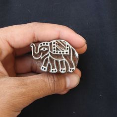 a hand holding a small carved elephant on top of a black surface with it's trunk in the air